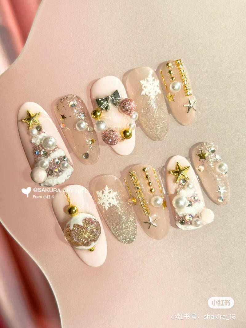 mau-nail-noel-dep__43__b27fe04ceeb74ea99a7a366e9b3e334d Bộ móng tay trang trí với hạt cườm, ngôi sao và bông tuyết trên nền màu hồng nhạt và vàng.