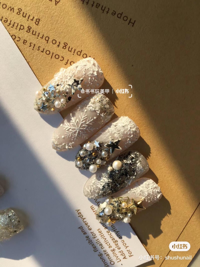 mau-nail-noel-dep__52__9685381fc909417399de17ffe318b23c Móng tay trang trí với hoa văn tuyết, ngôi sao và hạt cườm, nền giấy màu nâu và trắng.