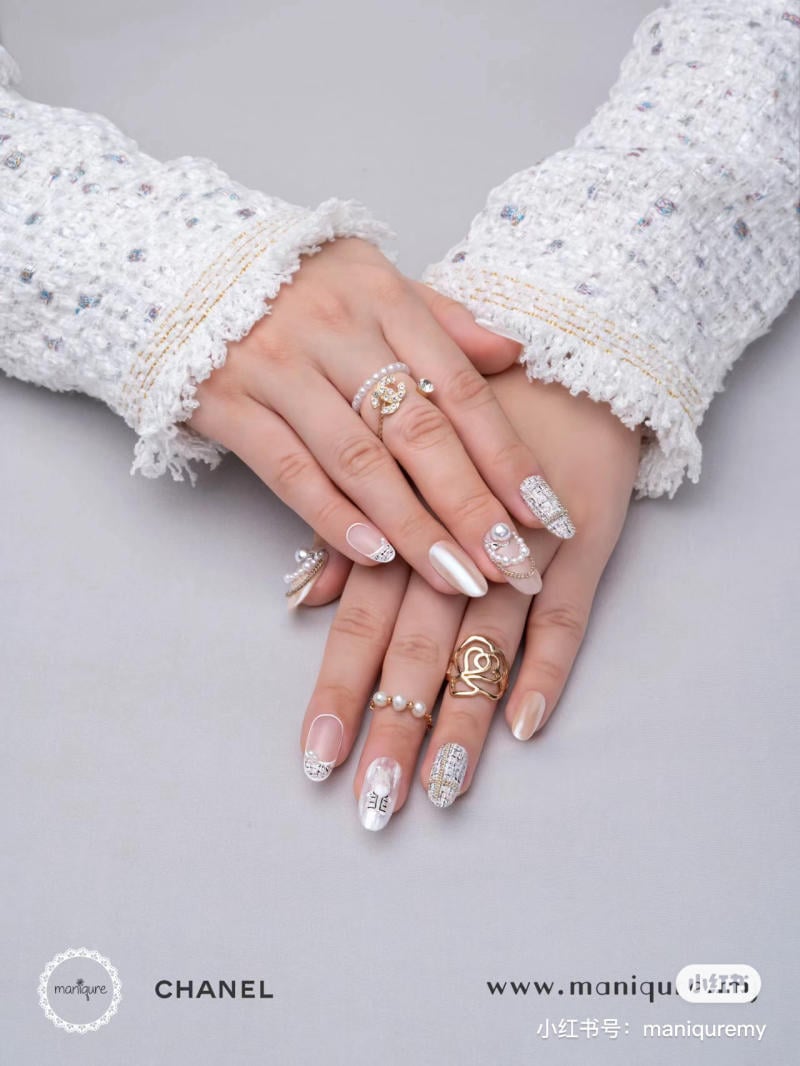 mau-nail-noel-dep__89__853abf88bad741a8a2172993c38e7c8b Hai bàn tay đan vào nhau với móng tay được trang trí cầu kỳ và đeo nhiều nhẫn thời trang.