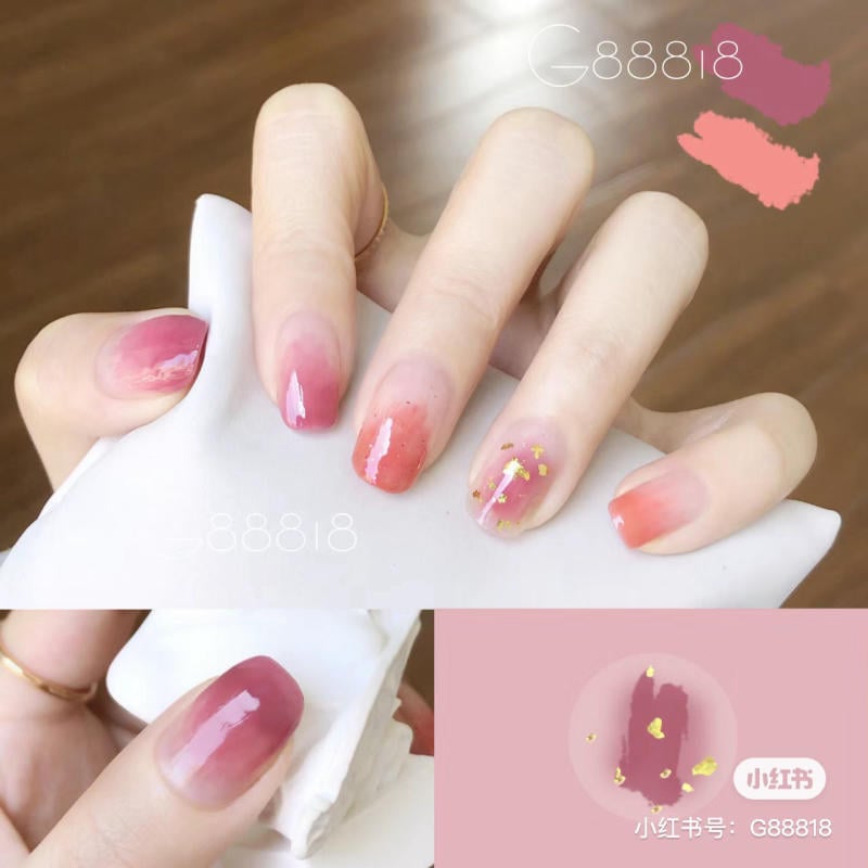 Bàn tay với móng tay được sơn màu hồng ombre và trang trí với họa tiết vàng lấp lánh.