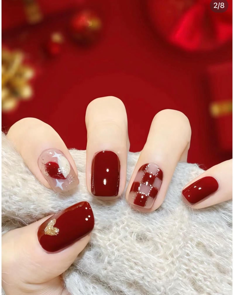 Bàn tay với móng tay được sơn màu đỏ, trang trí họa tiết tim và caro, trên nền vải len màu trắng.