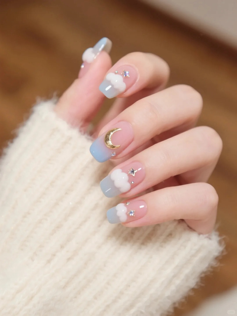 Móng tay được sơn màu pastel với họa tiết đám mây, ngôi sao và trăng lưỡi liềm, tạo vẻ dễ thương và tinh tế.