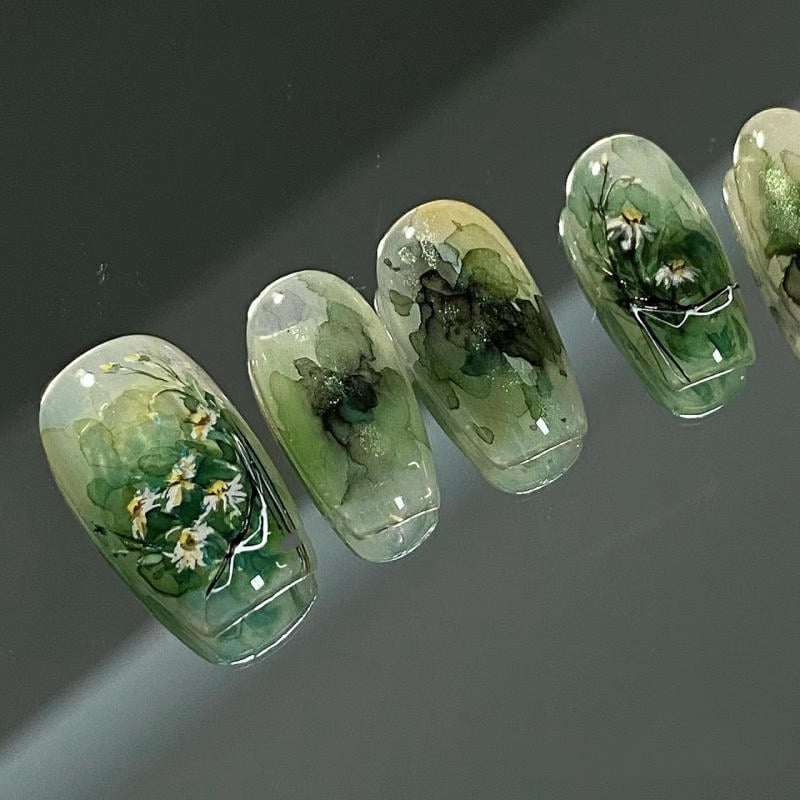 Mẫu móng tay xanh lá được trang trí hoa nhỏ và họa tiết tinh tế trên nền trong suốt.