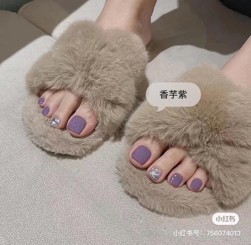 Bàn chân mang dép lông màu nâu, móng chân sơn màu tím nhạt, một móng có trang trí kim tuyến bạc.
