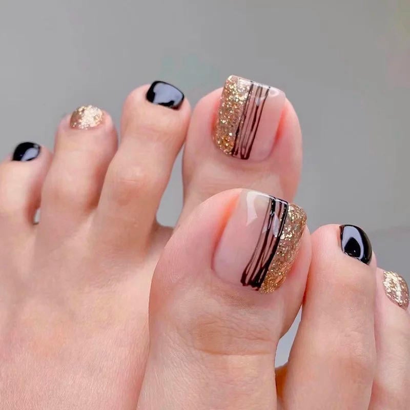 Bộ móng chân được sơn trang trí với màu đen và kim tuyến vàng, có họa tiết sọc tinh tế trên móng cái.