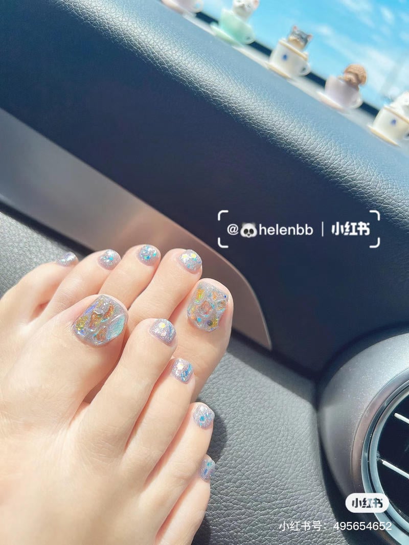 nai-chan-dinh-da__11__46595570b2b942729eadcde4760a4663 Bàn chân với móng chân được sơn màu ánh kim, chụp trong xe hơi dưới ánh sáng tự nhiên.