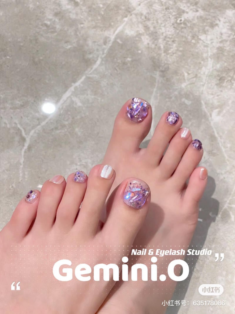 nail-chan-dinh-da__30__a145ba6adef747288cdecf0b9c46b4cb Bàn chân với móng được trang trí bằng sơn màu tím và trắng, nền gạch bóng.