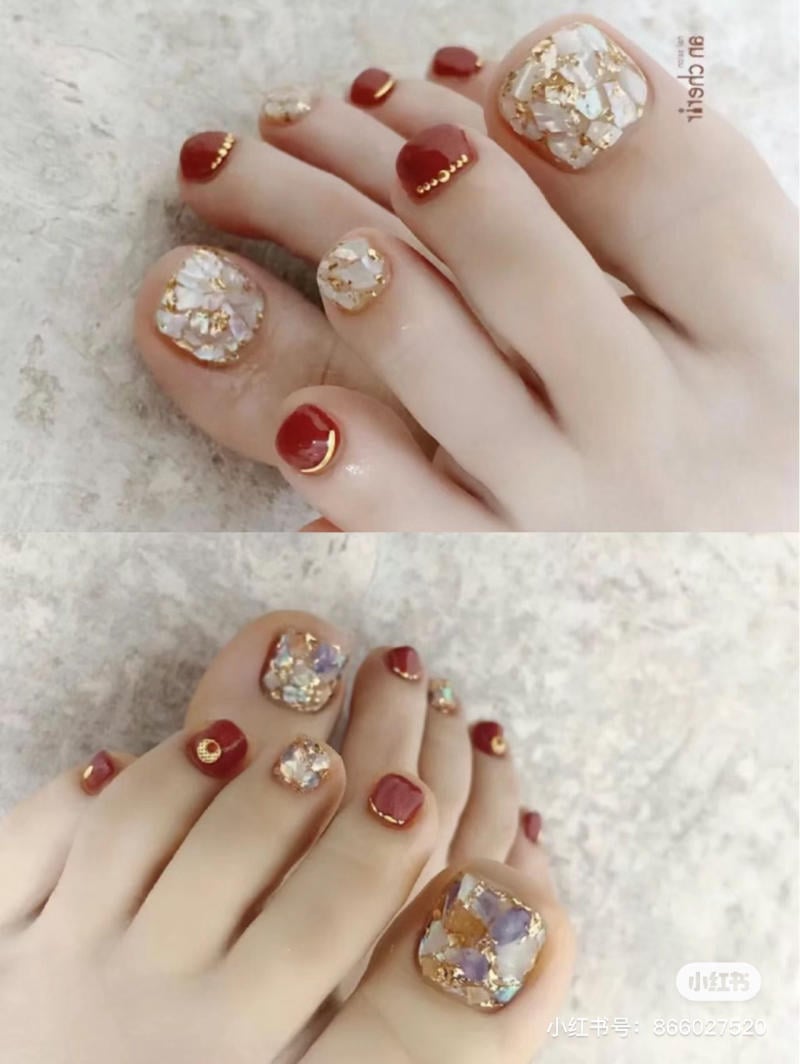 nail-chan-dinh-da__52__5d72820e9c8b473db60d6063869cf2f6 Móng chân được trang trí với họa tiết đá lấp lánh và màu đỏ, kèm chi tiết vàng nhỏ trên bề mặt.
