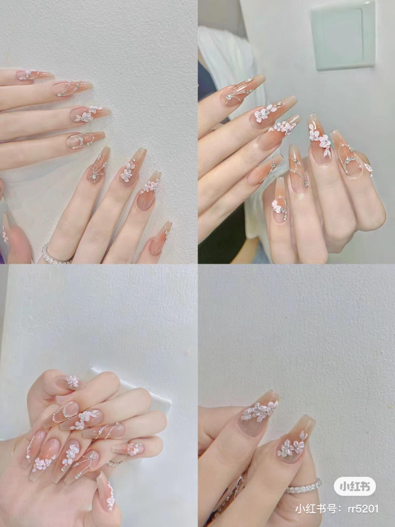 Bộ móng tay dài, trang trí hoa trắng và nhũ lấp lánh, được chụp từ nhiều góc độ khác nhau.