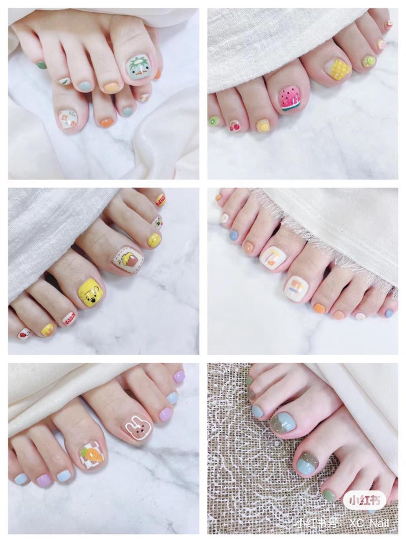Bộ sưu tập móng chân với các kiểu vẽ hoạt hình, hoa quả và màu sắc pastel khác nhau trên nền trắng.