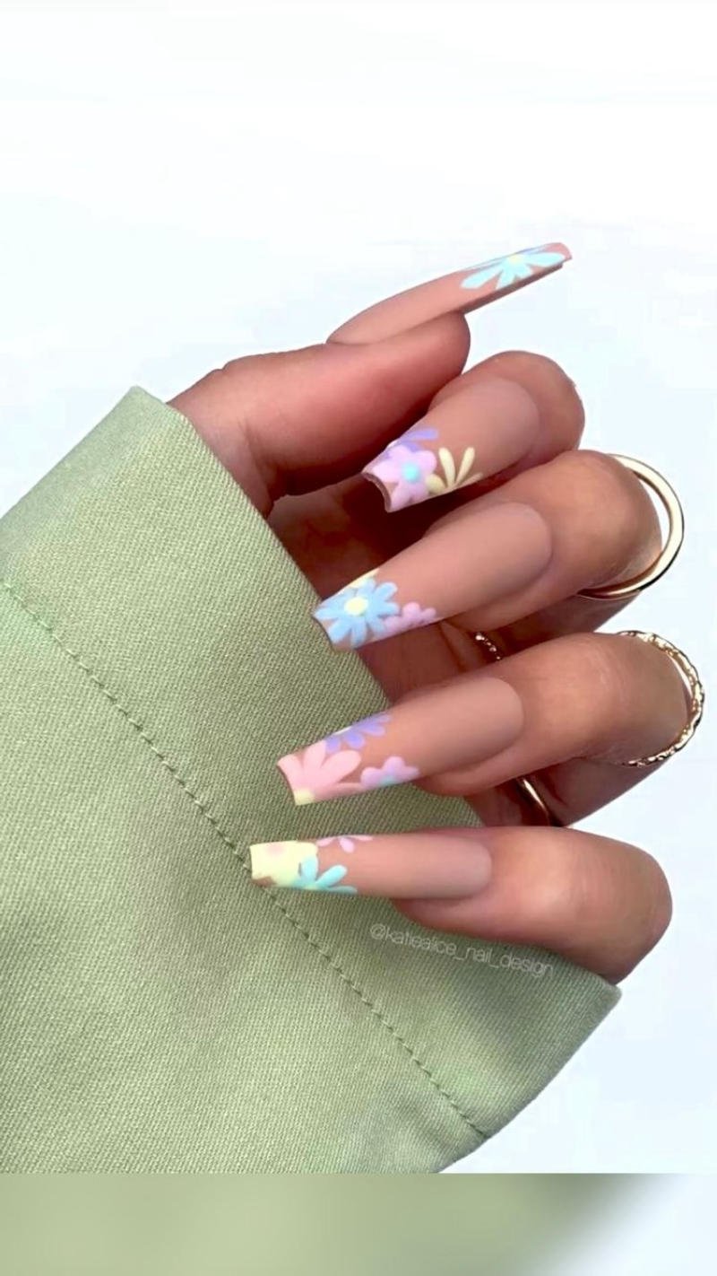 Bàn tay với móng tay dài, trang trí hoa màu pastel, áo tay dài màu xanh nhạt.
