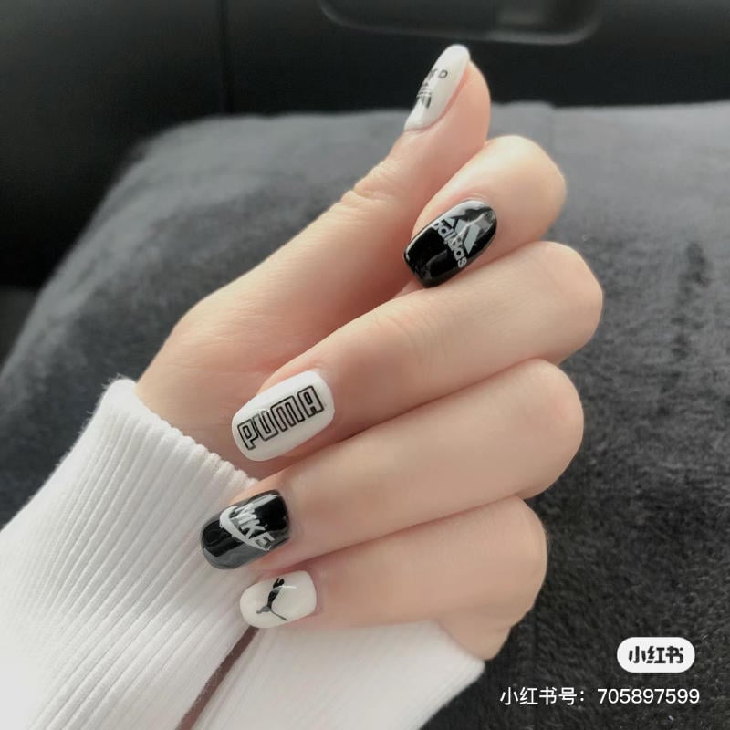 Bàn tay với móng tay được trang trí bằng các logo thương hiệu, nền trắng và đen.