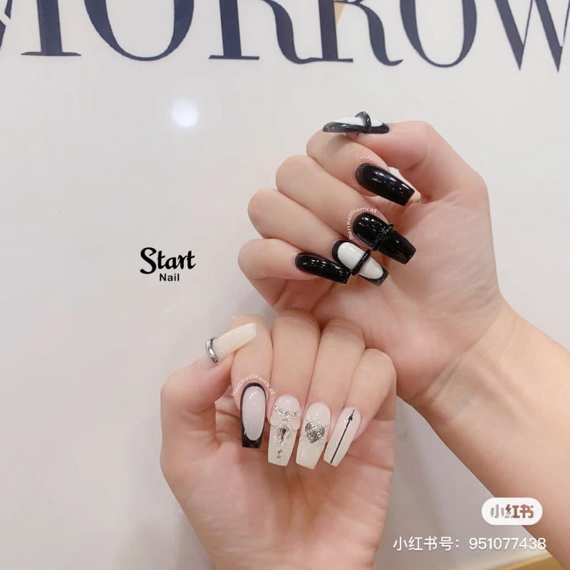 Hai bàn tay với móng tay được trang trí họa tiết đen trắng và đính đá, nền chữ "Start Nail".