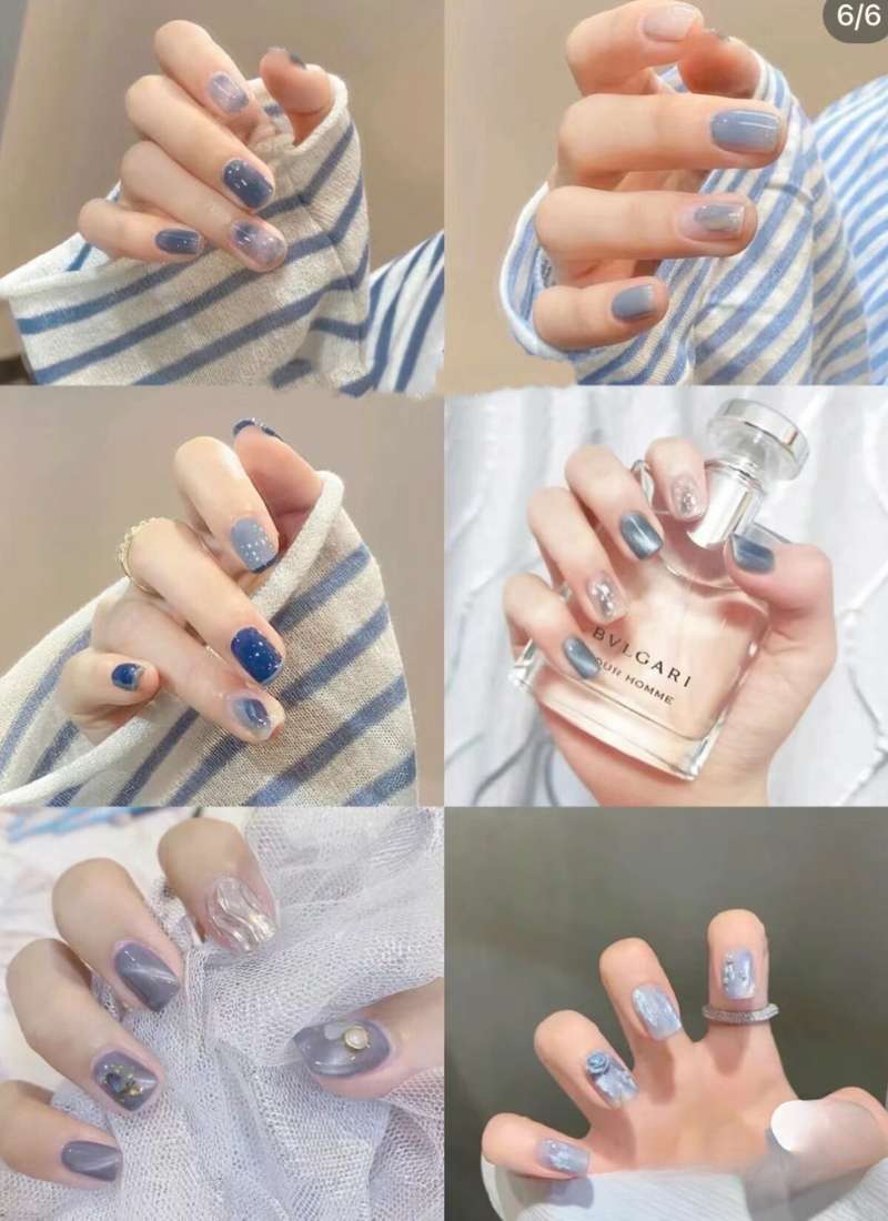 Bàn tay với móng tay được sơn màu xanh, trang trí đa dạng, cầm chai nước hoa và vải sọc.