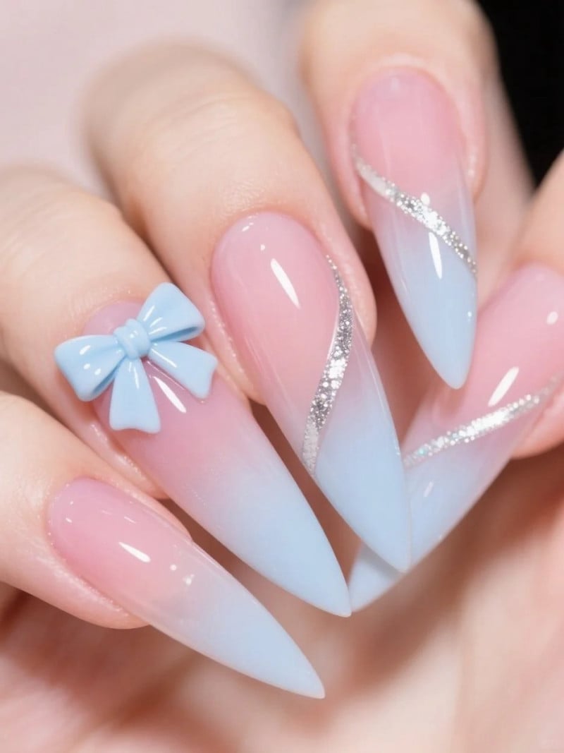 Móng tay nhọn ombre hồng xanh, trang trí nơ xanh và họa tiết kim tuyến bạc.