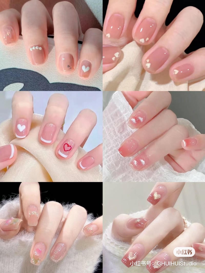 Bộ móng tay với nhiều mẫu trang trí khác nhau, chủ yếu là họa tiết trái tim và ngọc trai trên nền màu hồng nhạt.