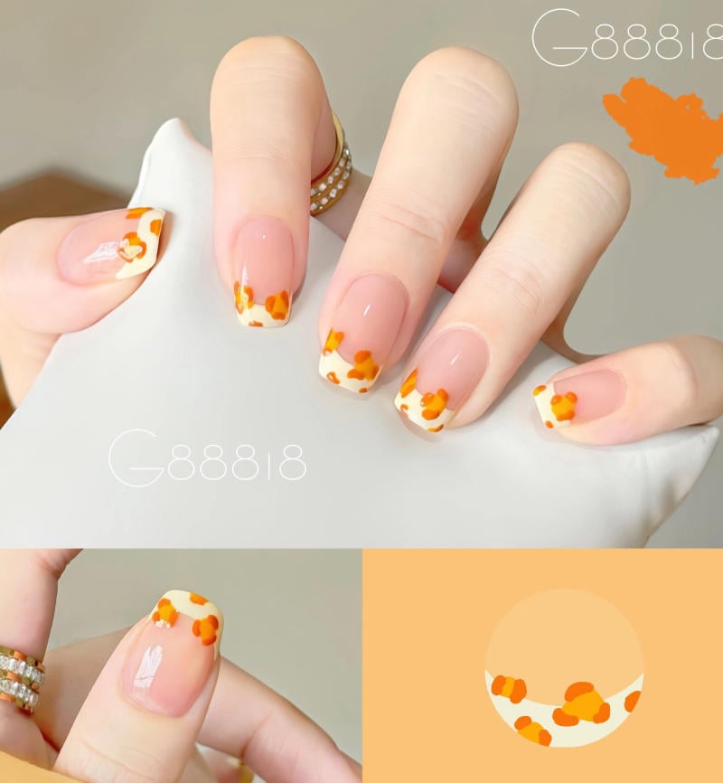 B&agrave;n tay với m&oacute;ng tay sơn kiểu Ph&aacute;p, họa tiết cam trắng, cầm t&uacute;i m&agrave;u trắng.