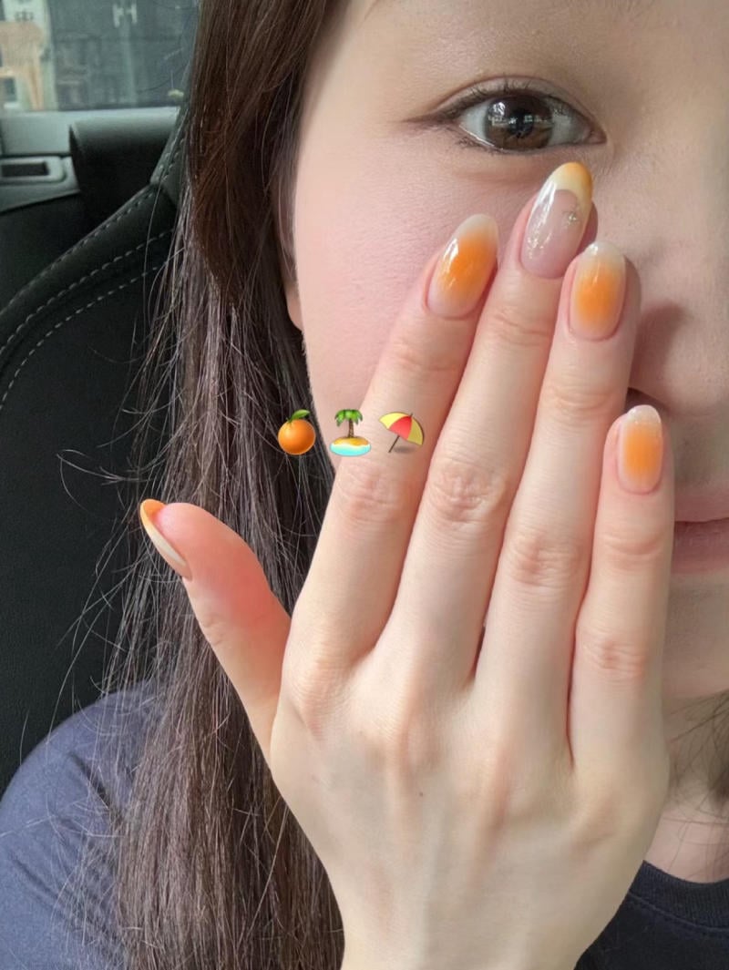 Người cầm tay che mặt, m&oacute;ng tay sơn m&agrave;u cam ombre, nền l&agrave; ghế xe hơi.