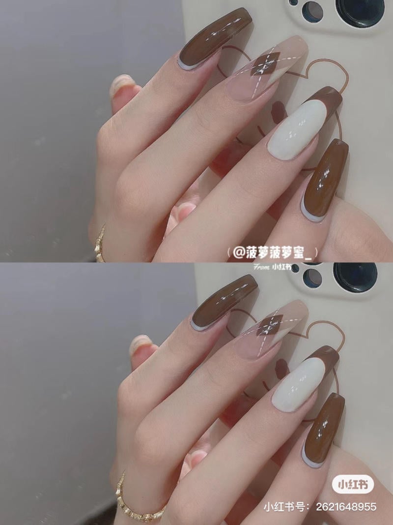 Bàn tay với móng tay dài, sơn màu nâu và trắng, cầm một chiếc điện thoại có ốp lưng họa tiết đơn giản.