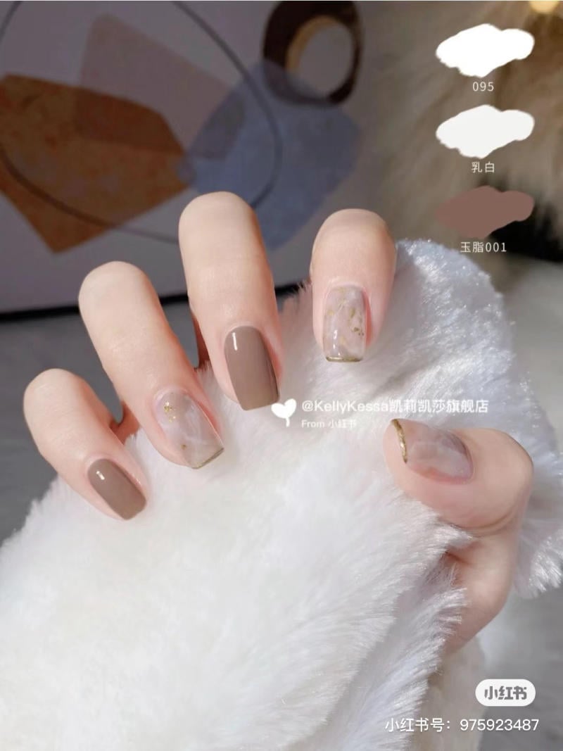Bàn tay với móng tay sơn màu nâu và trang trí họa tiết, chạm vào một bề mặt lông mềm mại.