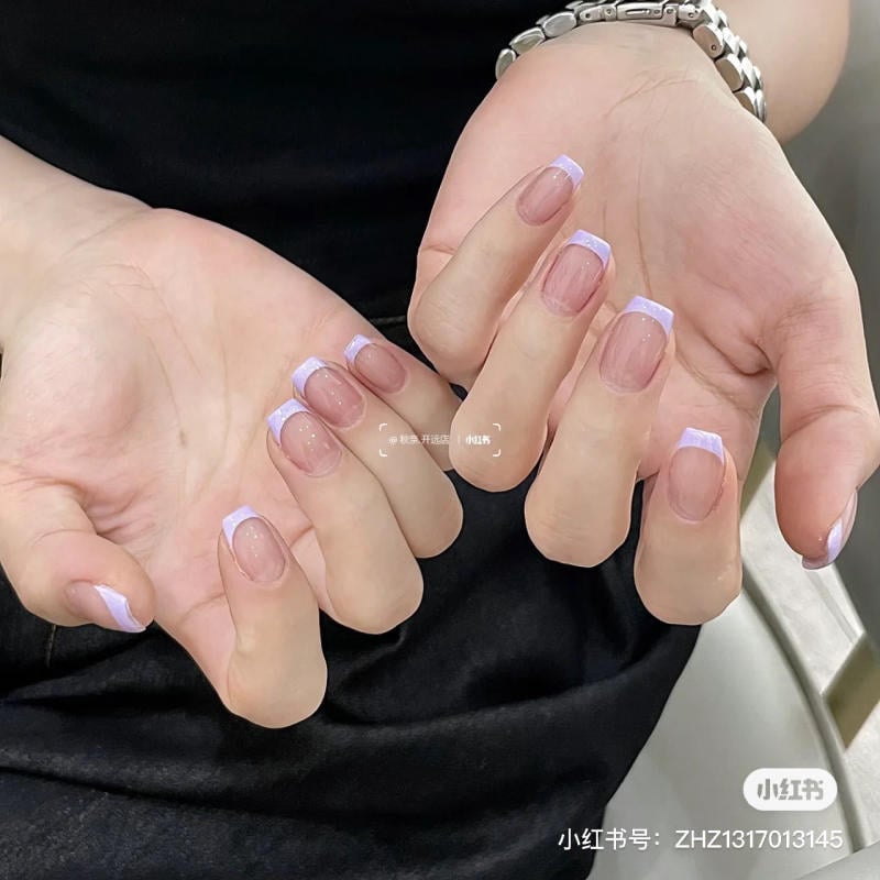 nail-mau-tim__11__60f3fd1185954359b2ee0119928f6b8f Hai bàn tay với móng tay được sơn kiểu Pháp, đầu móng màu trắng tím trên nền móng tự nhiên.