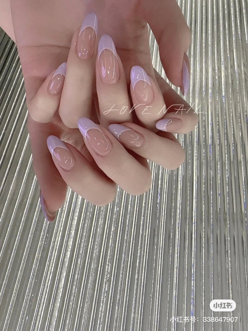 nail-mau-tim__13__89e8ab30d15545b4b9e5ad6bfa770df7 Bàn tay với móng tay được sơn màu hồng nhạt và trắng, đặt trên nền sọc kim loại sáng bóng.