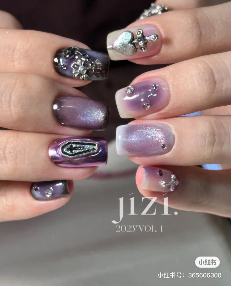 nail-mau-tim__27__d493fdd3fc0d423796221a2618987bb1 Bàn tay với móng tay thiết kế cầu kỳ, màu sắc và đính đá lấp lánh.