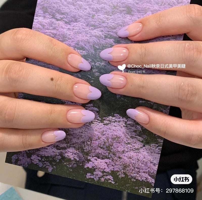 nail-mau-tim__3__0fdfc9d0ef5e41ad94cf5d929bbb7ba3 Móng tay sơn kiểu Pháp màu tím nhạt, tay cầm bức ảnh nền hoa tím.