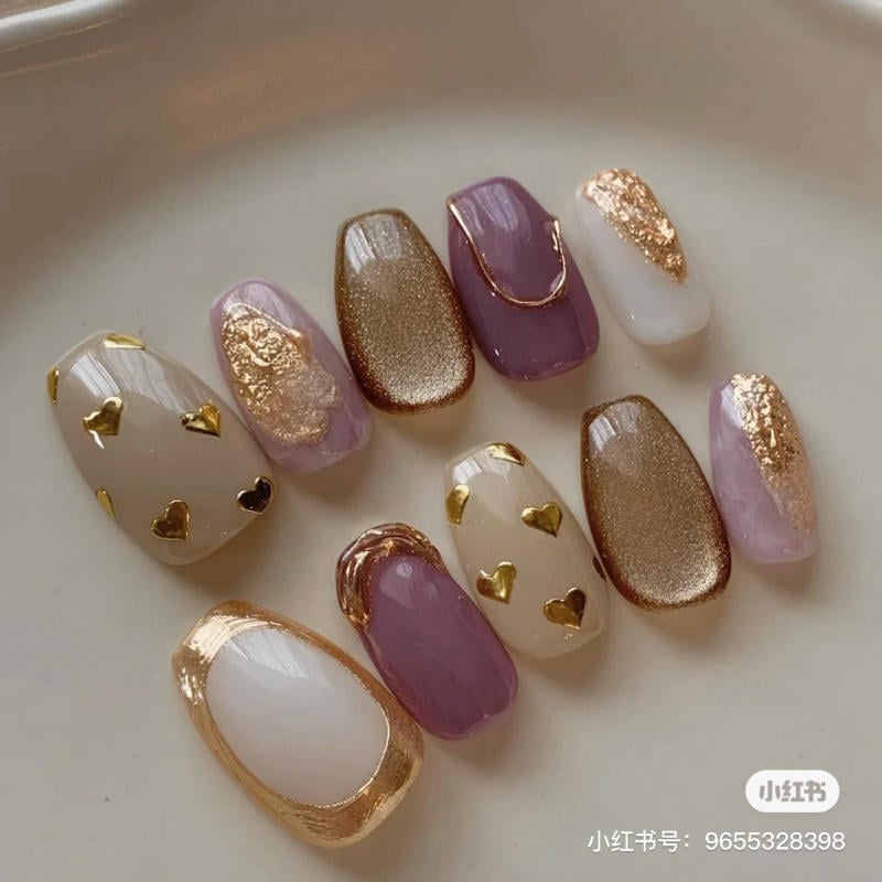 nail-mau-tim__51__2f312469c31641d8bfe97a1b2c415324 Bộ móng giả với nhiều màu sắc và họa tiết vàng, tím, trắng, trang trí hình trái tim và viền ánh kim.