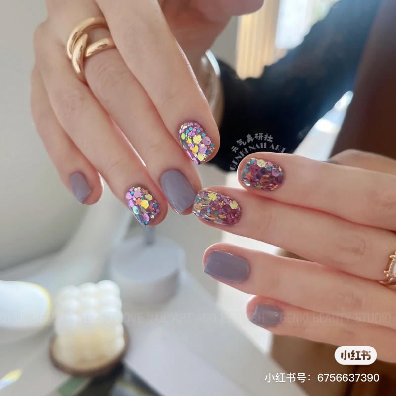 nail-mau-tim__56__a478aab44b2841869634fd49efd4e075 Bàn tay với móng tay được sơn màu xám và trang trí kim tuyến lấp lánh.