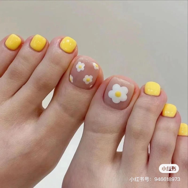 Bàn chân với móng chân sơn màu vàng và trang trí hoa trắng trên nền trong suốt.