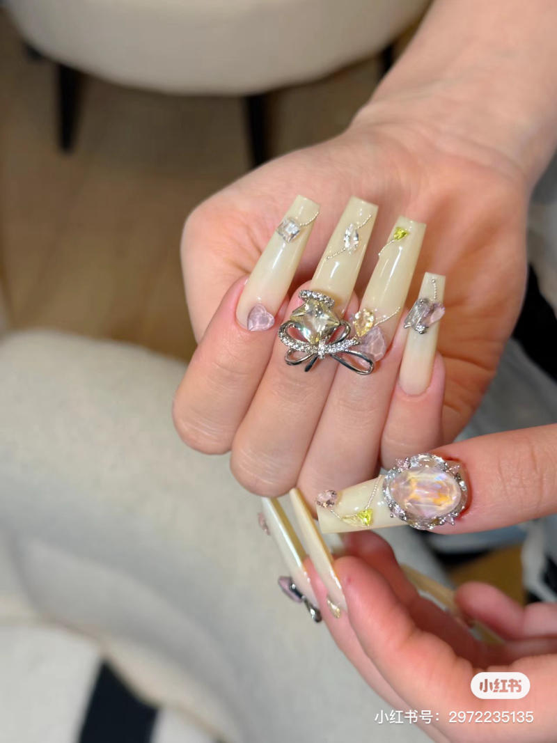 Bàn tay với móng tay dài, trang trí họa tiết và đá quý lấp lánh.