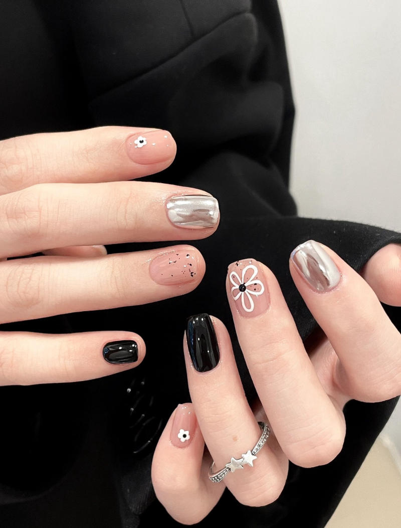 Bàn tay với móng tay được sơn đa dạng, gồm màu đen, bạc, hoa nhỏ và họa tiết khác nhau.