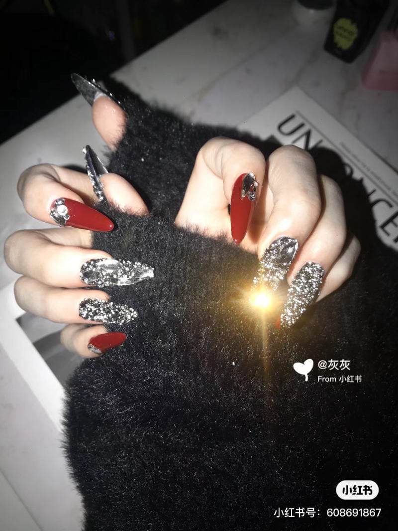 nail-mong-nhon-tron__15__b0a2fde790ec44a593f67d3e3ab99aeb Bàn tay đeo găng lông màu đen, móng tay dài được trang trí màu đỏ và ánh bạc lấp lánh.