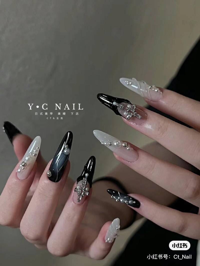 nail-mong-nhon-tron__5__b6f353c752c0456d84a144a3712254b6 Bàn tay với móng tay dài được trang trí hoa văn đen trắng và đính đá lấp lánh.