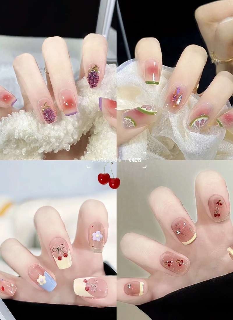 Bộ móng tay trang trí với họa tiết trái cây và hoa, gồm màu sắc đa dạng như tím, xanh và đỏ.