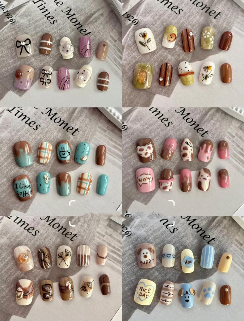 Bộ móng tay giả với nhiều họa tiết và màu sắc khác nhau trên nền giấy in chữ.