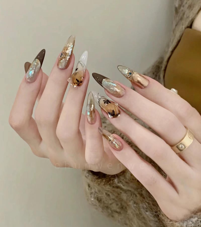 Bàn tay với móng tay dài được trang trí nghệ thuật với họa tiết và màu sắc đa dạng, tạo vẻ nổi bật và sáng tạo.