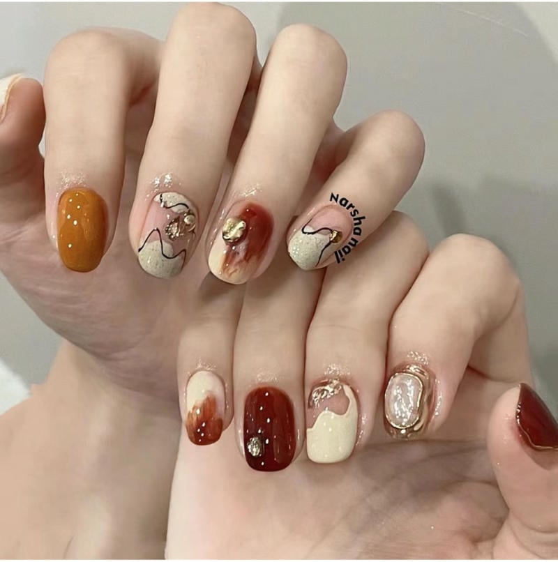 Bàn tay với móng tay được trang trí nghệ thuật, màu sắc đa dạng và họa tiết độc đáo.