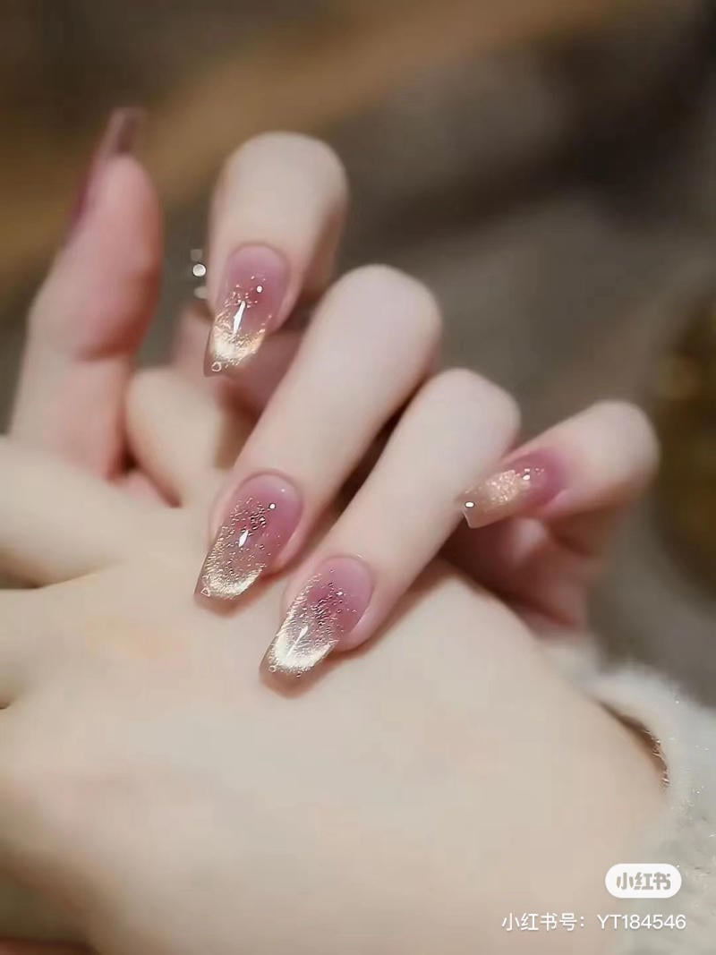 Bàn tay với móng tay được sơn màu hồng nhạt, trang trí hiệu ứng lấp lánh.