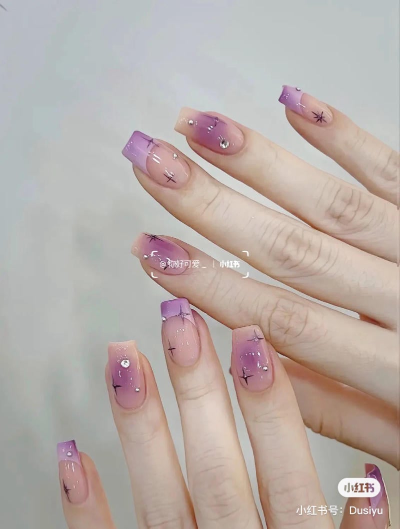 Bộ móng tay được sơn màu tím nhạt, trang trí họa tiết và đính đá lấp lánh.