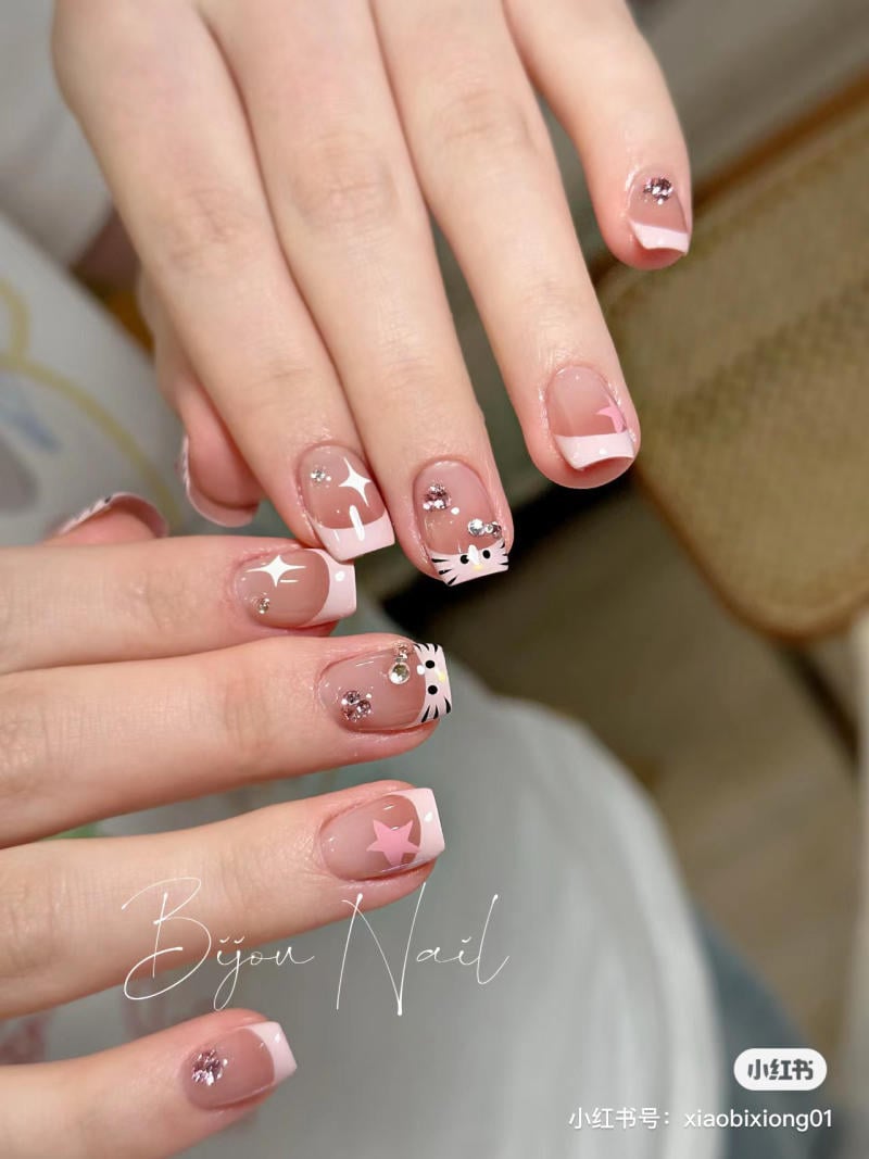 Bàn tay với móng tay được trang trí họa tiết dễ thương, có màu hồng và ánh kim lấp lánh.