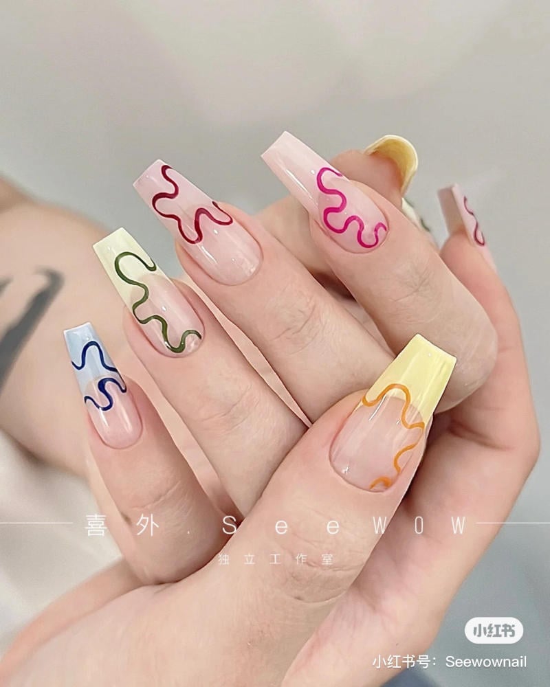 Bàn tay với móng tay được sơn màu pastel, trang trí họa tiết uốn lượn nhiều màu sắc khác nhau.