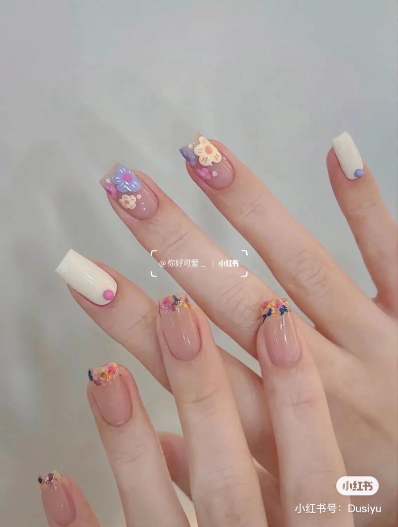 Bàn tay với móng tay được trang trí bằng họa tiết hoa và hình động vật, nổi bật với màu sắc tươi sáng và đa dạng.