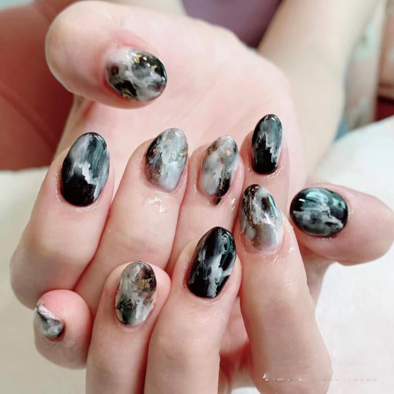 nail-van-da-dep__16__ad137d43c78a45a08f3ecd185ac95c75 Bàn tay với móng tay sơn màu đen và xám, họa tiết vân đá, ánh kim loại.