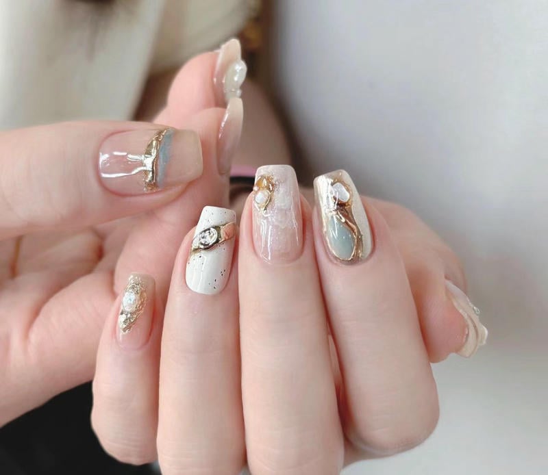 nail-van-da-dep__18__c0c846a8dd9541e2ad7f8cf9d780eeb3 Bộ móng tay được trang trí cầu kỳ với màu sắc nhạt, đính đá và họa tiết vàng, tạo nên vẻ sang trọng và tinh tế.