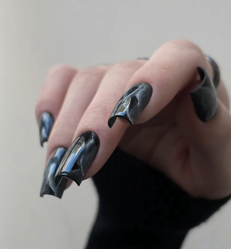 nail-van-da-dep__24__d13ff82de566464b85980fdb95669109 Bàn tay với móng tay dài được sơn màu đen bóng, họa tiết vân đá, nổi bật trên nền nhạt.