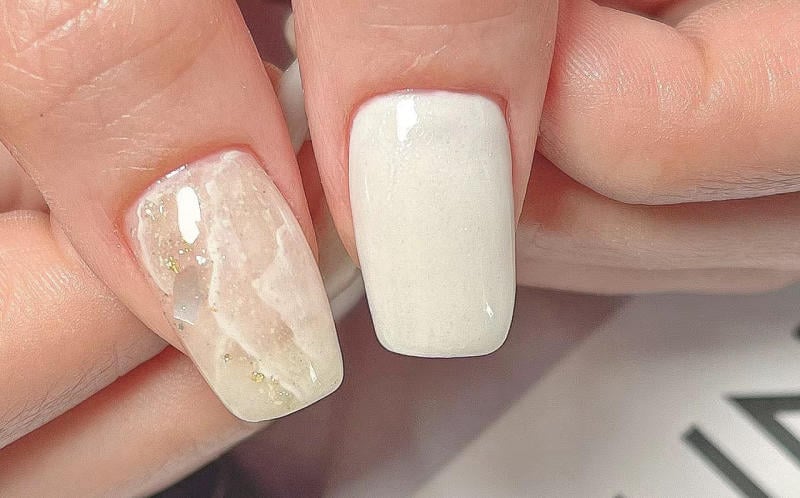 nail-van-da-dep__28__014686bced9e4f5490bff8c705ce89e5 Hai móng tay được sơn màu trắng và kiểu vân đá cẩm thạch với chi tiết lấp lánh.