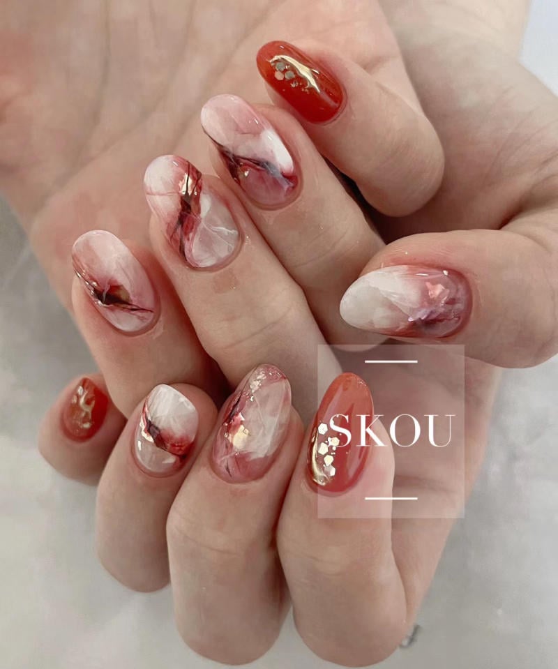 nail-van-da-dep__29__2502cfcc74964571aae96c4e754a919e Bàn tay với móng tay được trang trí nghệ thuật, có màu đỏ, trắng và họa tiết ánh kim lấp lánh.