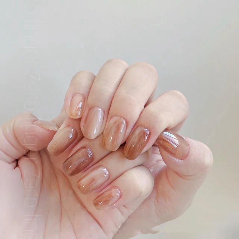 nail-van-da-dep__32__42e48c543ee24fc58c68c174c3eb2521 Bàn tay với móng tay được sơn màu nâu bóng đa sắc, nền màu xám nhạt.